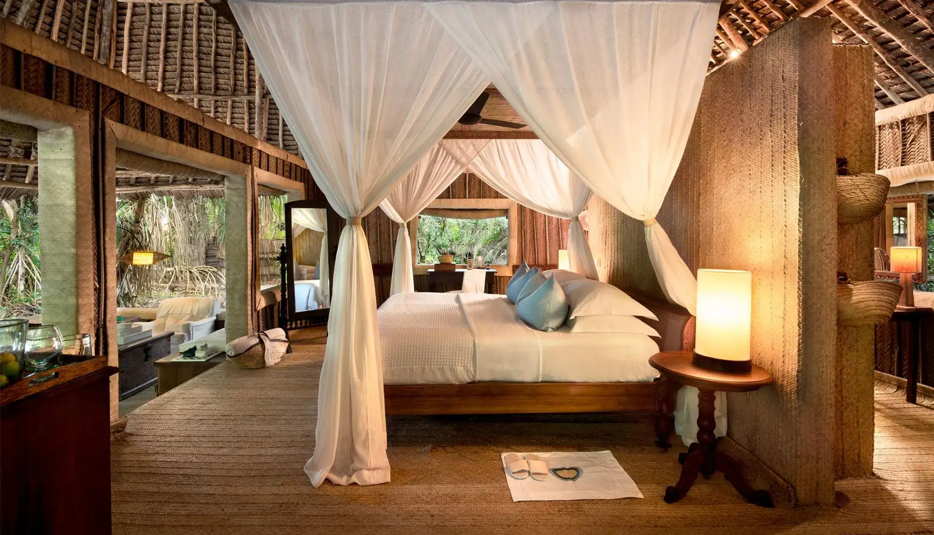 Overwater villas at Mnemba Island Lodge surrounded by turquoise waters and coral reefs in Zanzibar.