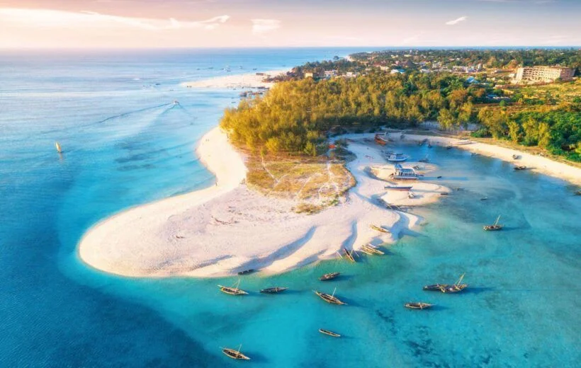 Aerial view of Zanzibar’s white-sand beaches, turquoise waters, and traditional dhow boats along the Indian Ocean.
